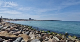 Blick von der Moe in Warnemünde über die Ostsee zum Strand und dem Hotel Neptun im Juli 2022